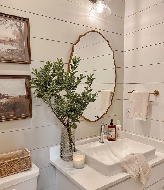Sherwin Williams Jogging Path on shiplap in a bathroom with a gold framed mirror above a white vanity and sink.
