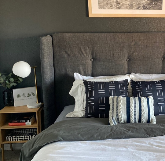 Behr Cracked Pepper on a bedroom wall behind a plush upholstered headboard