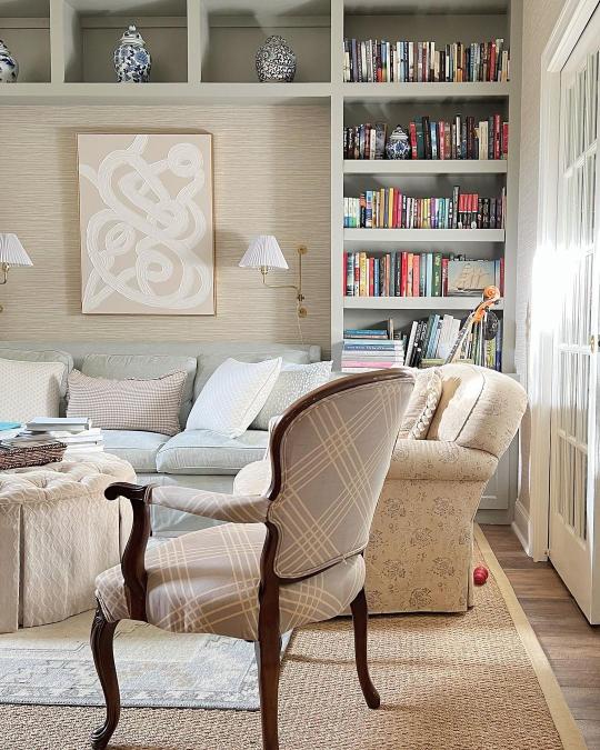 Benjamin Moore Fieldstone on a bookshelf in a living room with grasscloth wallpaper and neutral overstuffed furniture.