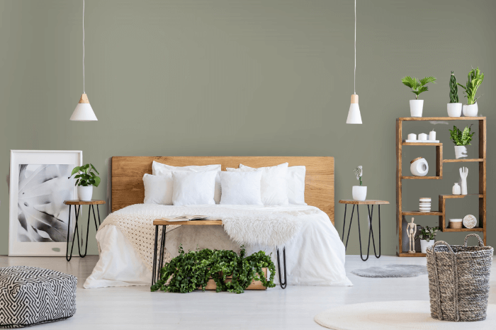 Benjamin Moore dry Sage on a bedroom wall behind a wood framed bed with white linens and a bookshelf