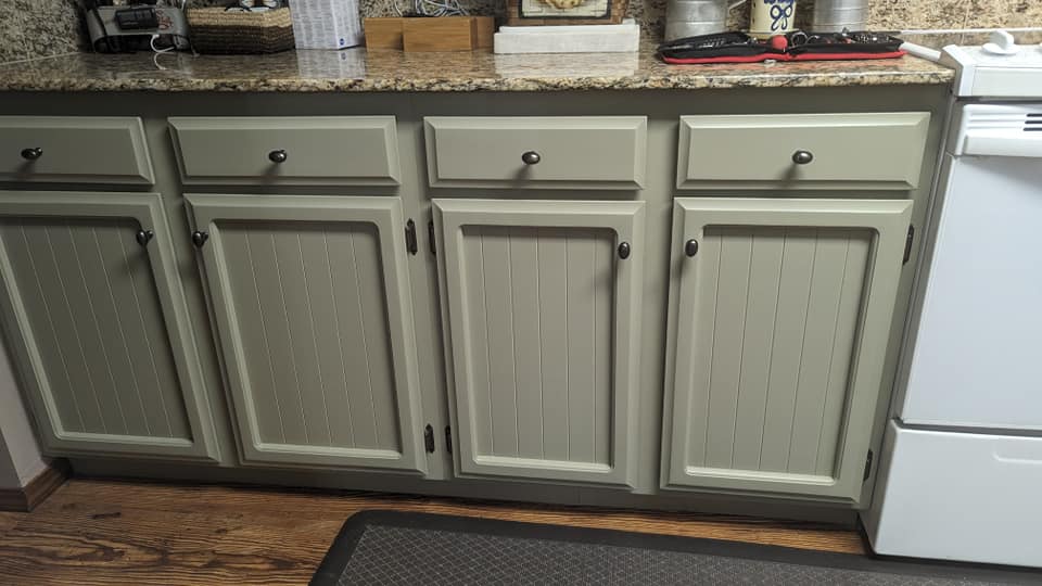 Benjamin Moore Dry Sage on lower cabinets with warm wood floors and warm stone countertops