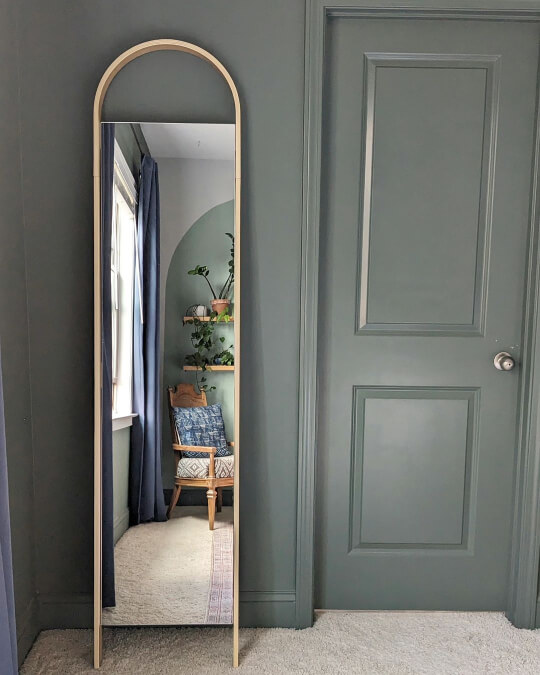 Behr Heritage Park drenching a bedroom with an arched gold mirror resting on the way, reflecting a white alcove