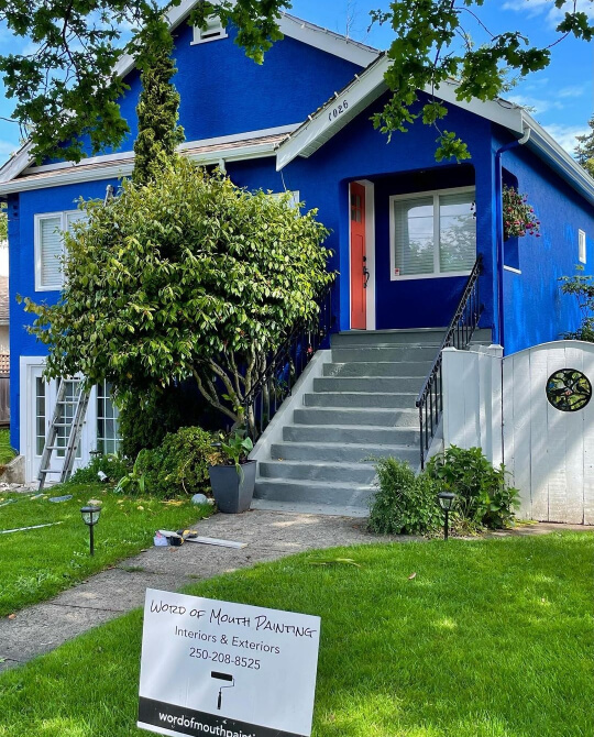 Benjamin Moore Dark Royal Blue on a stucco exterior with gray stairs and a rusty coral door.