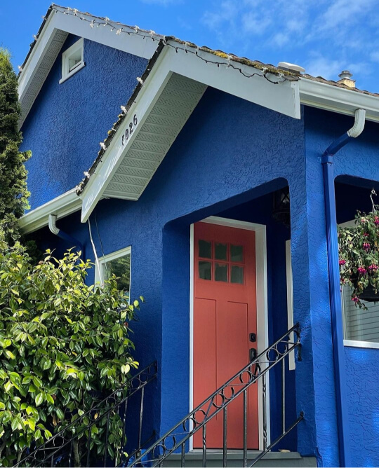 Benjamin Moore Dark Royal Blue on a freshly painted stucco exterior with a rust colored door and white soffits.
