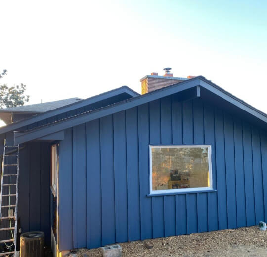 Benjamin Moore Newburyport Blue on a vertical siding exterior with a mustard door.