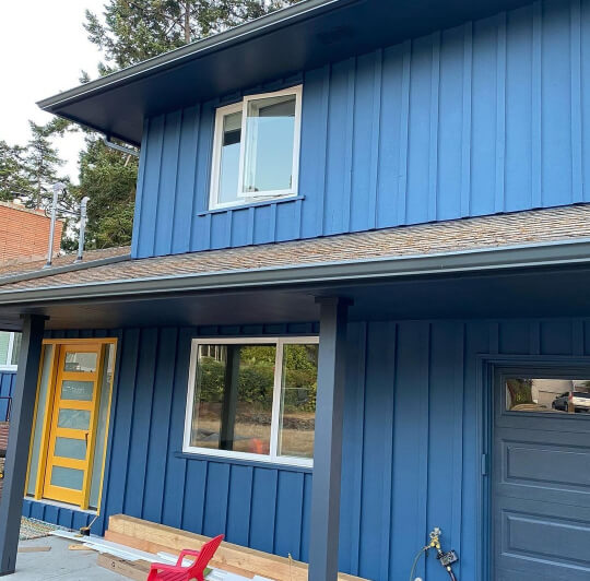 Benjamin Moore Newburyport Blue on a vertical siding exterior with a mustard door.