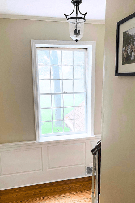 Sherwin Williams Universal Khaki color on walls in a stairwell with white wainscoting on the lower quarter of the wall.