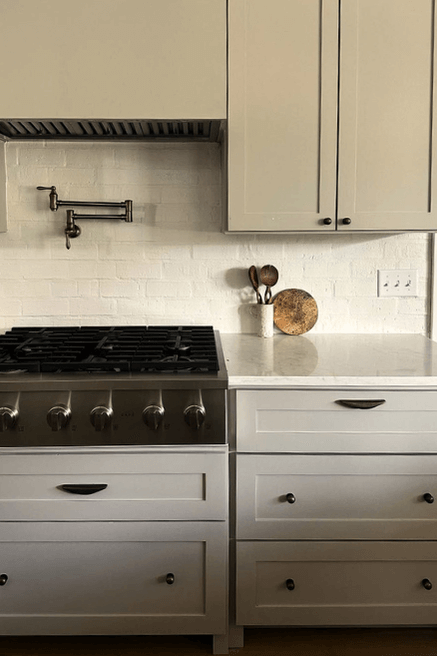 A Sherwin Williams Universal Khaki color on kitchen cabinets with white brick backsplash.