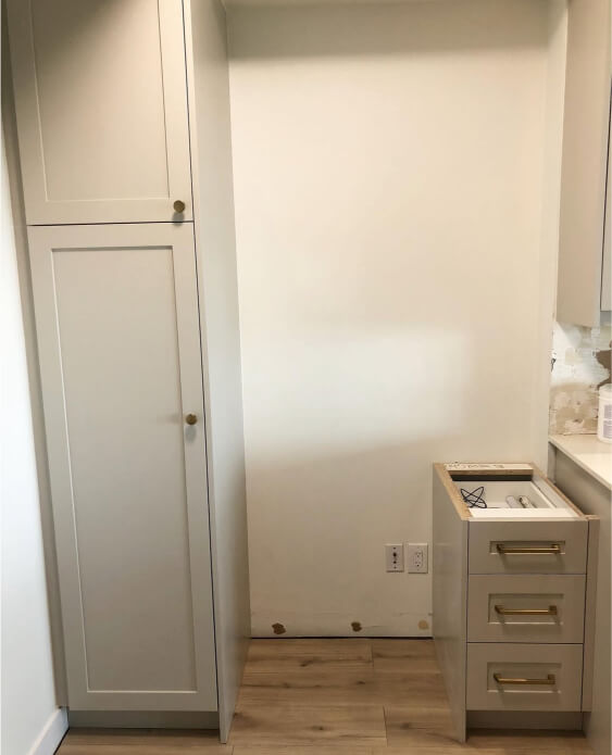 Benjamin Moore Revere Pewter cabinets with a built-in design, featuring shaker-style doors and round brass knobs.