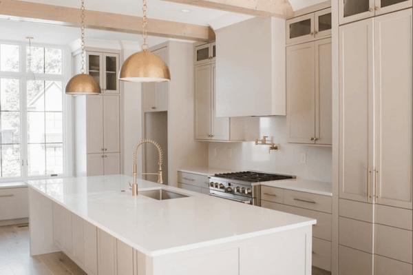 Benjamin Moore Stone Hearth on kitchen cabinets in a creamy white open plan main floor with copper pendant lights.