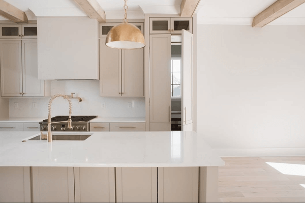 Benjamin Moore Stone Hearth on kitchen cabinets in a creamy white open plan main floor with copper pendant lights.