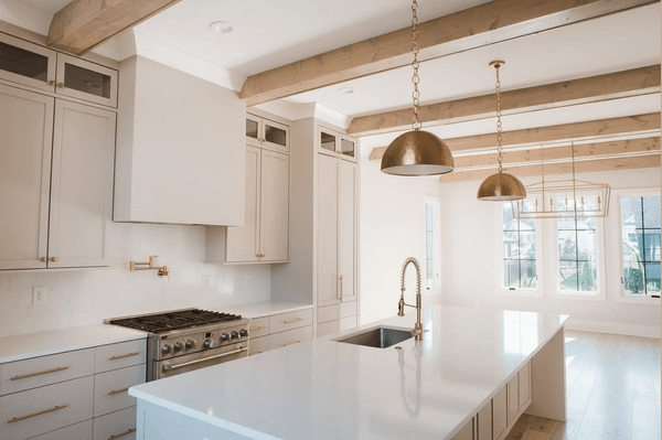 Benjamin Moore Stone Hearth on kitchen cabinets in a creamy white open plan main floor with copper pendant lights.