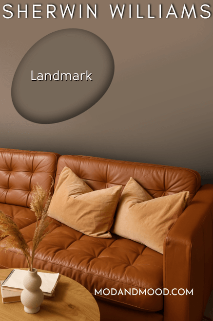 Sherwin Williams Landmark paint swatch over a background of that color on a living room wall with a brown leather sofa.
