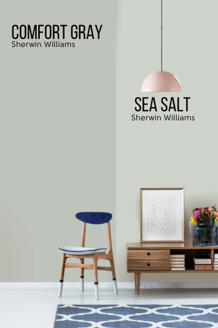 Sherwin Williams Comfort Gray on half of a wall and Sea Salt on the other half behind a wood console table and a blue chair.