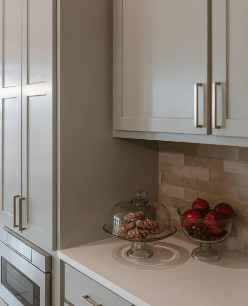 Evergreen Fog at 50% on upper cabinets and pantry with a textured stone backsplash.