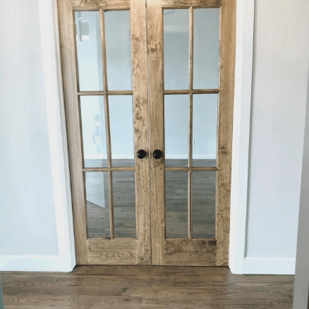 Sherwin Williams Drift of Mist where it looks cool and silver on either side of a walnut door with glass inserts.