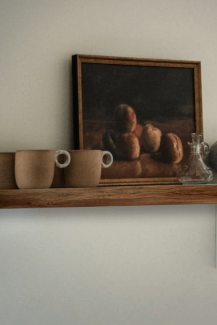 Sherwin Williams White Duck on a wall with a wood shelf, brown clay coffee cups, and an oil painting.