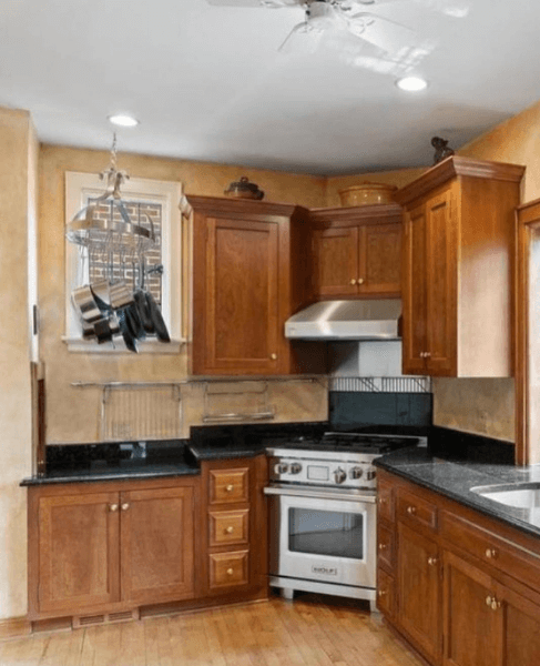A warm wood kitchen with dated oak cabinets before being painted with Evergreen Fog.