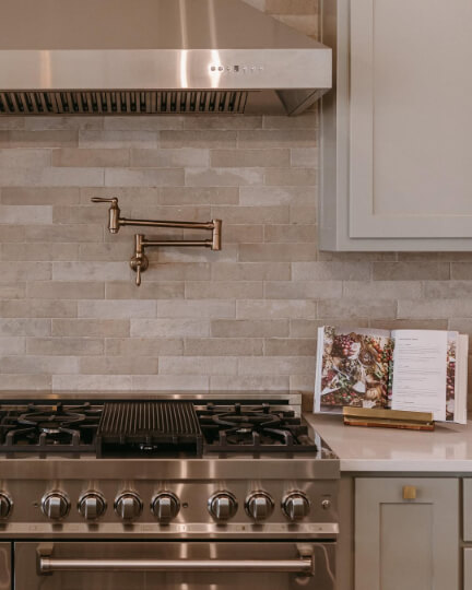 Close up of Sherwin Williams Evergreen Fog at 50% on kitchen cabinets with a textured stone backsplash