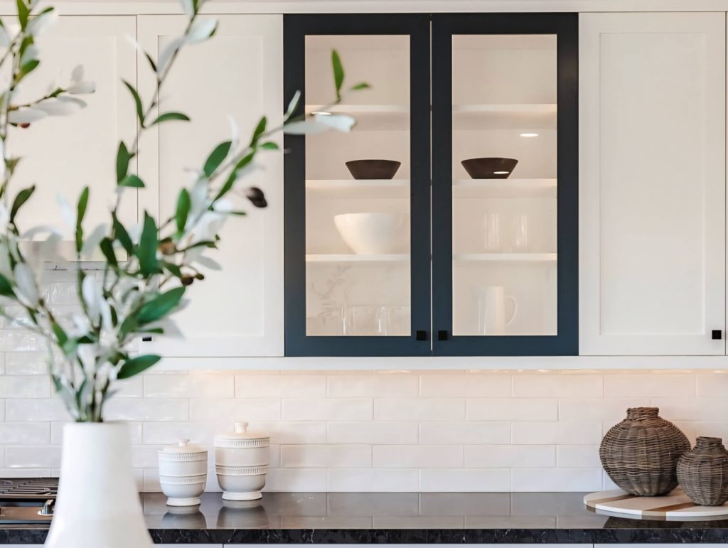 White upper kitchen cabinets where they look like Sherwin Williams White Duck, with one set of black framed glass cabinets i.n the middle