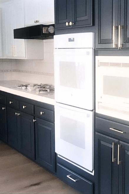 Benjamin Moore Blue Note on kitchen cabinets with white appliances and countertops.