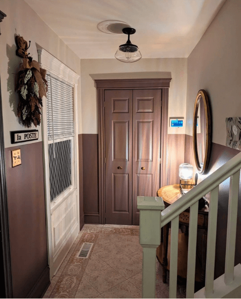 Benjamin Moore Pale Oak on the top 1/3 of a wall and Cinnamon Slate on the lower 2/3 in warm night lighting.