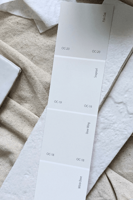 Pale Oak white and off white color strip from Benjamin Moore features Pale Oak, Seapearl, Dove Wing, and White Dove. The color strip sits over white tile on a canvas background.