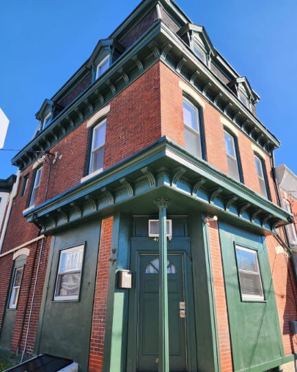 Benjamin Moore Backwoods lookalike on the front door, awnings, and around the windows on a historic looking shop front with red brick on the rest.