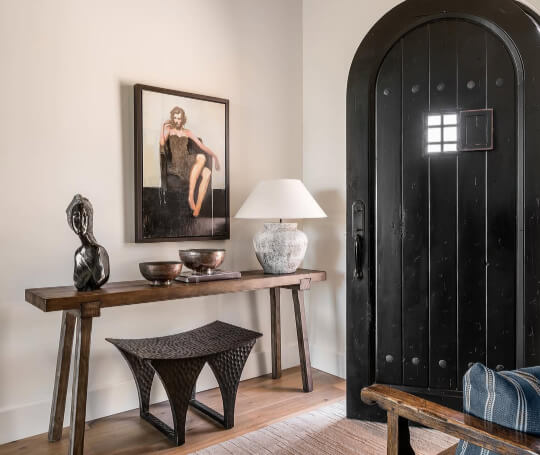 Sherwin Williams Creamy on walls in an entrance beside an arched black wooden front door.