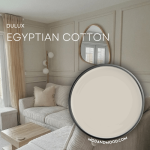 Dulux Egyptian Cotton swatched on a paint lid over a background of the color in a living room.