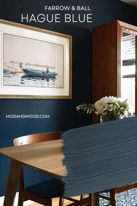 Farrow and Ball Hague Blue swatched over the color on a wall in a dining room.
