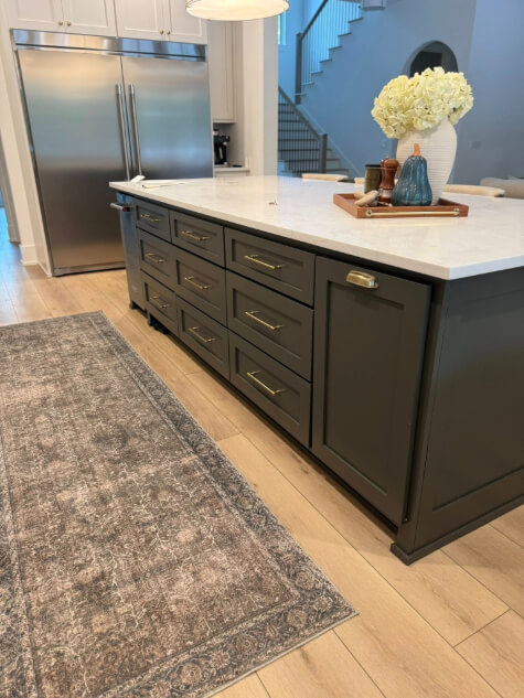 Benjamin Moore Dragon's Breath on a kitchen island with light wood floors and a long rug.