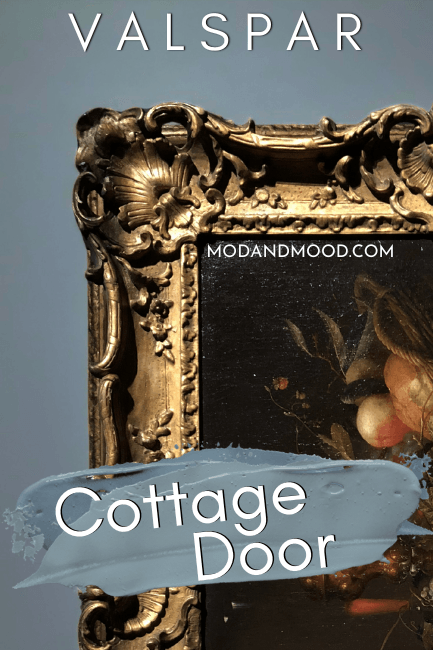 Valspar Cottage Door swatched over a photo of the color on a wall behind a gold frame